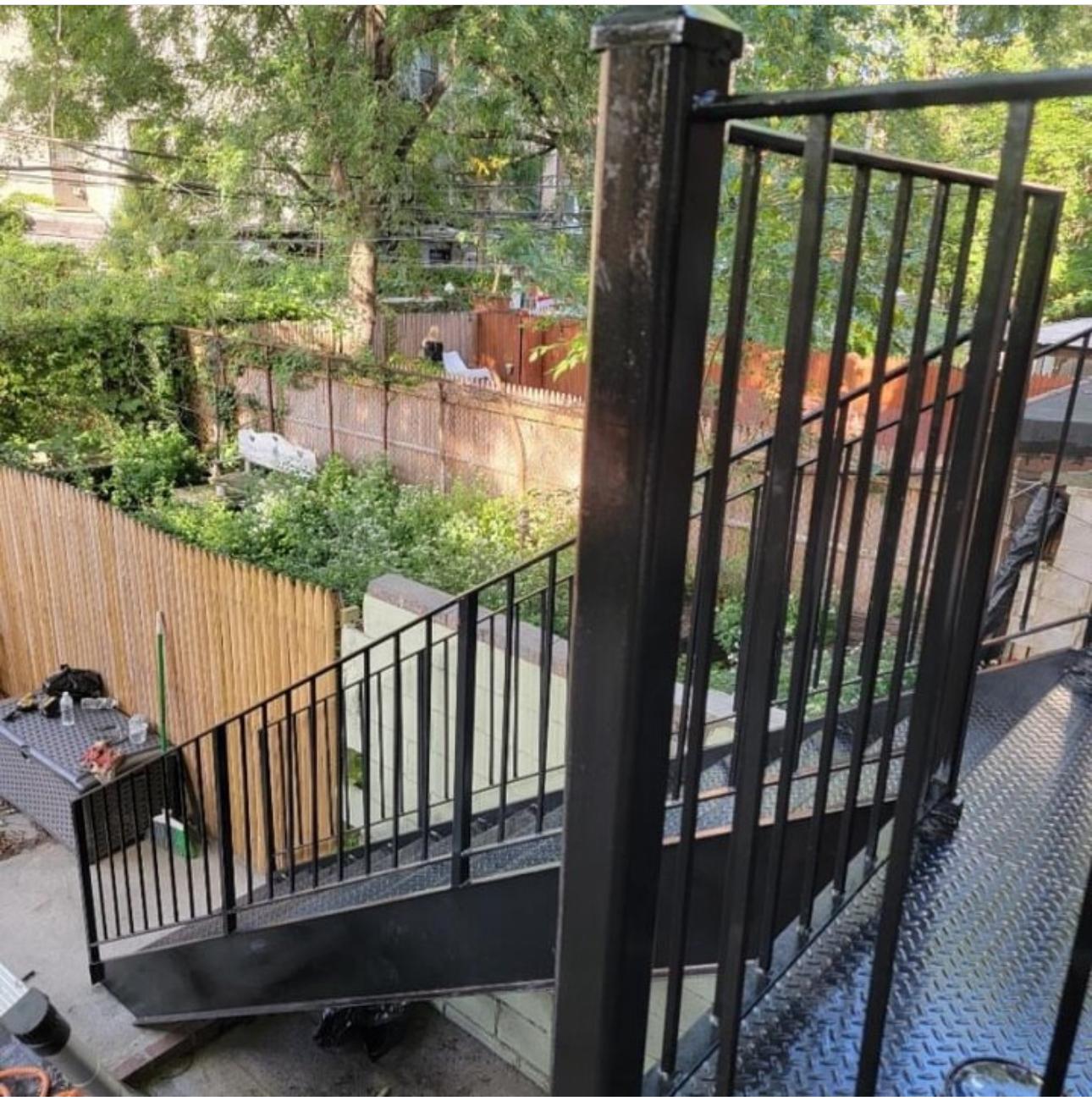 Steel deck and stair with picket railing behind a city residence