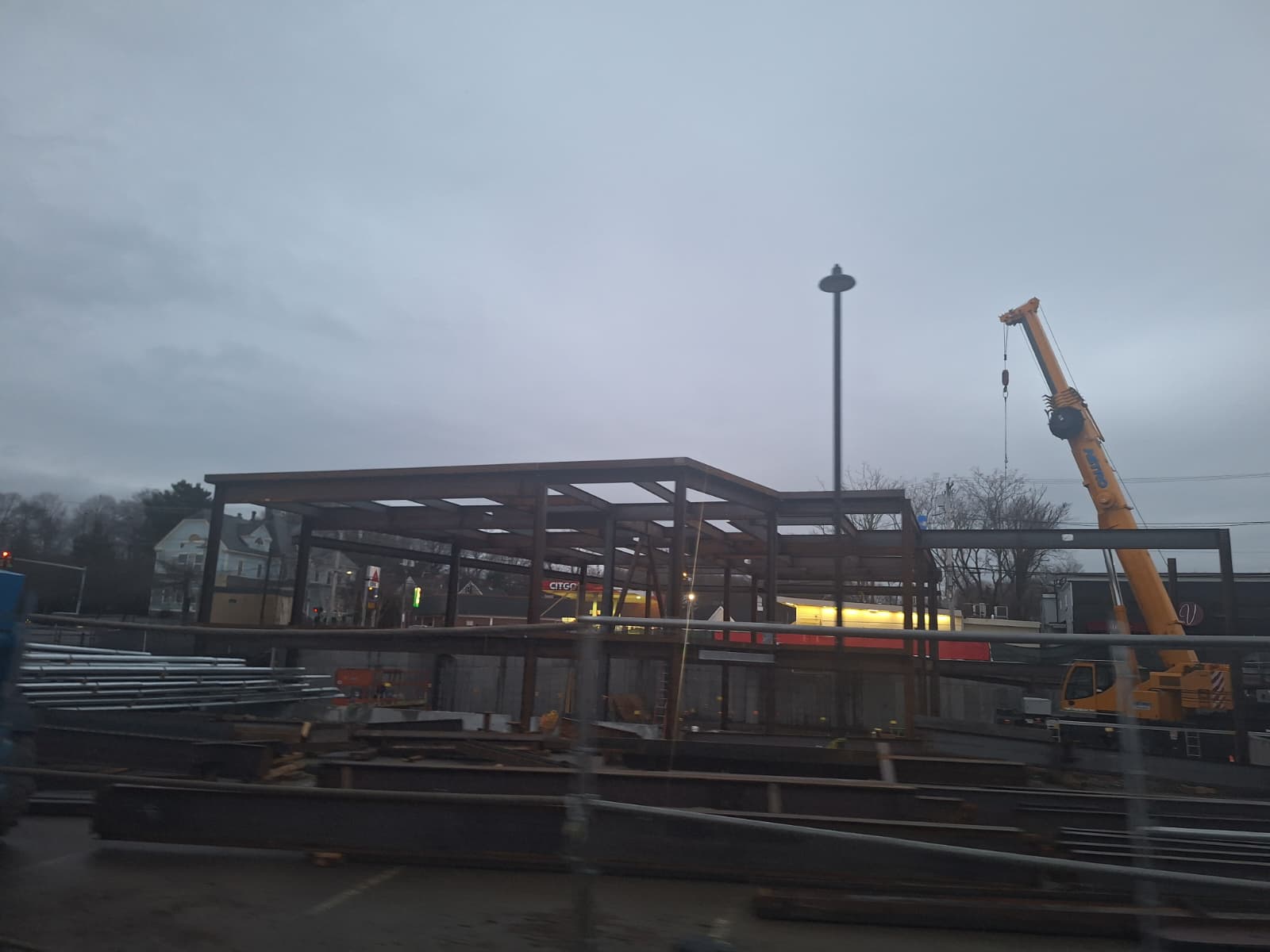 Two-level steel frame erected at dusk with a crane on site