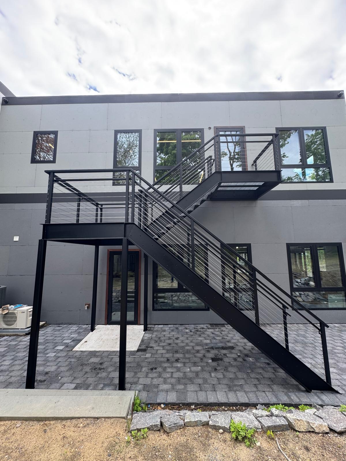 Steel egress stair and elevated landing on a commercial facade