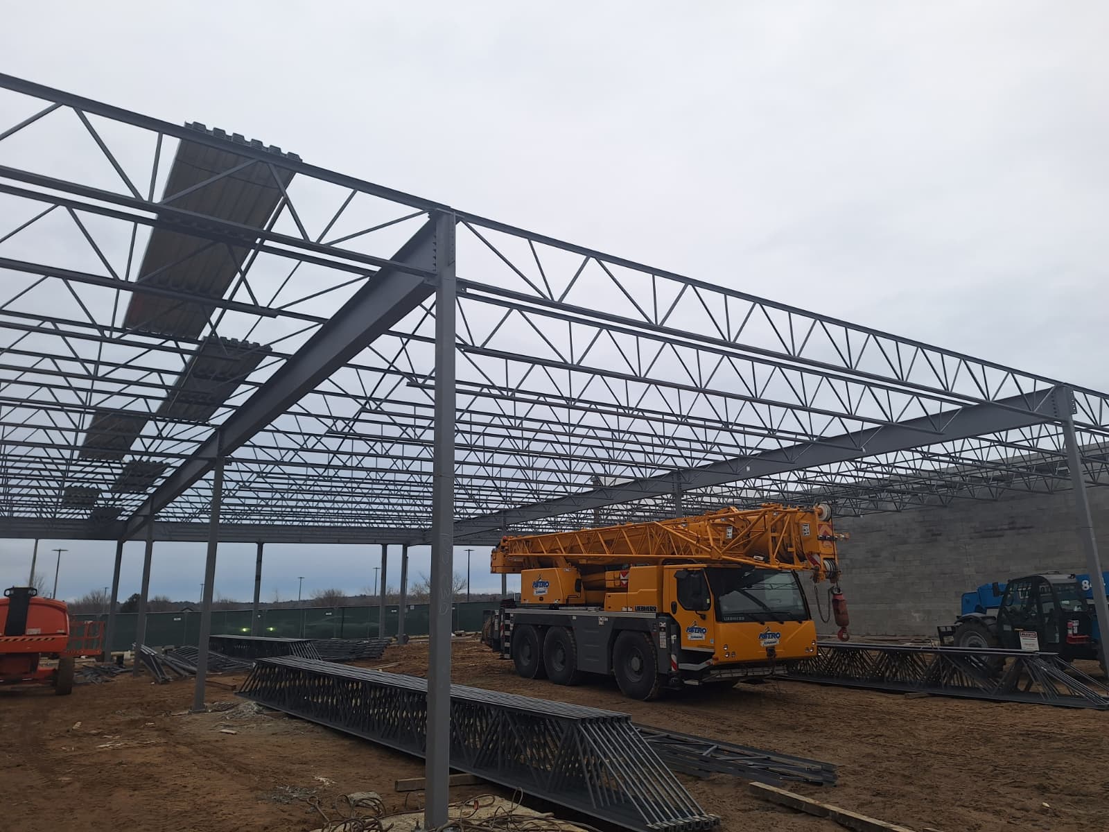 Long-span steel frame with joists and a mobile crane on site