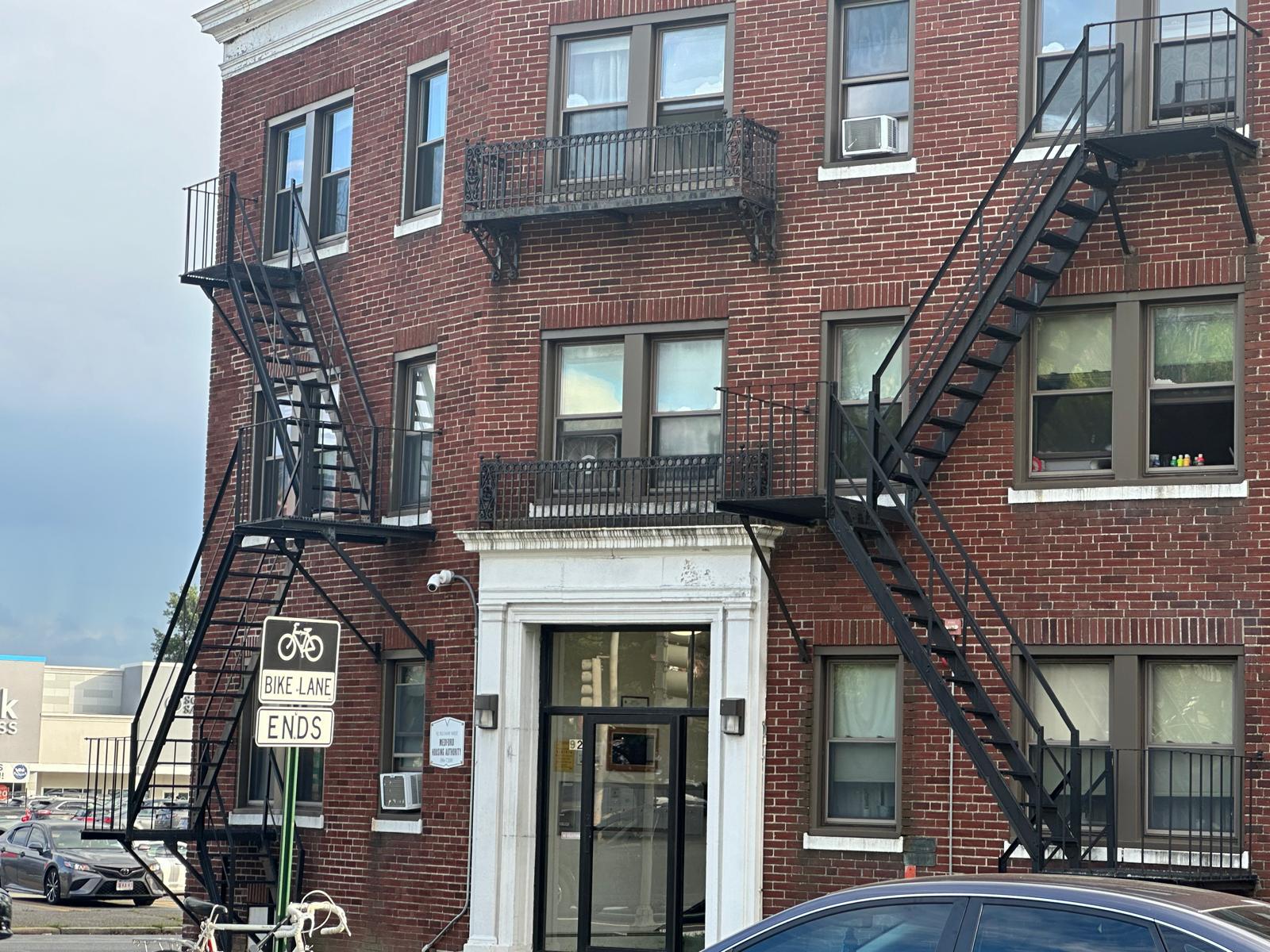 Steel fire escape stairs and balconies on a brick apartment building