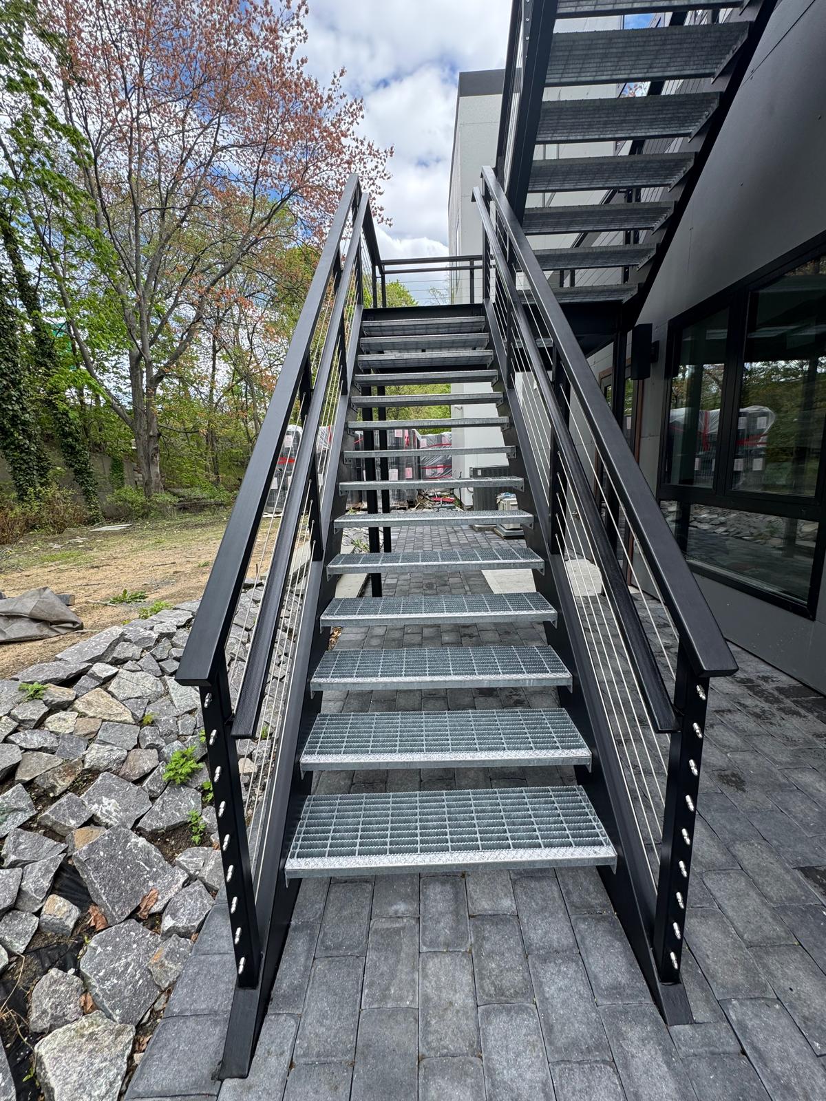 Galvanized grating treads on a steel stair with cable railing
