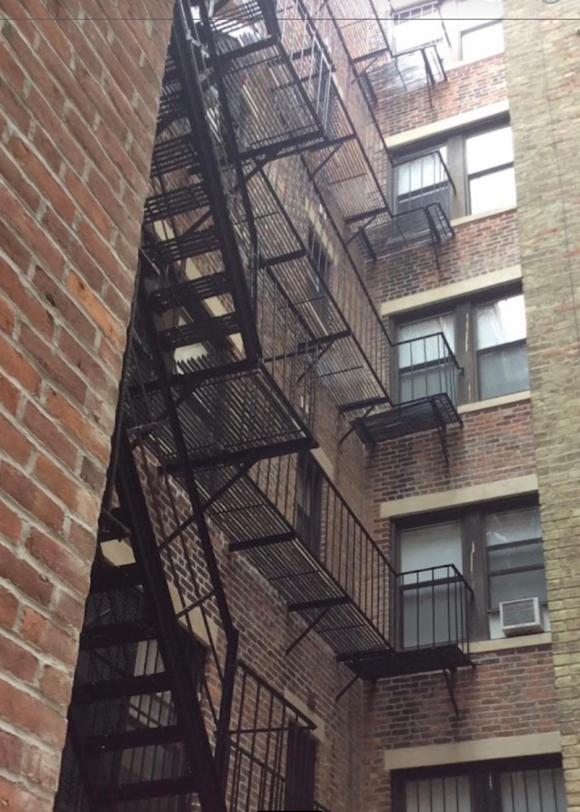 Multi-story black steel fire escape with balconies on a brick building