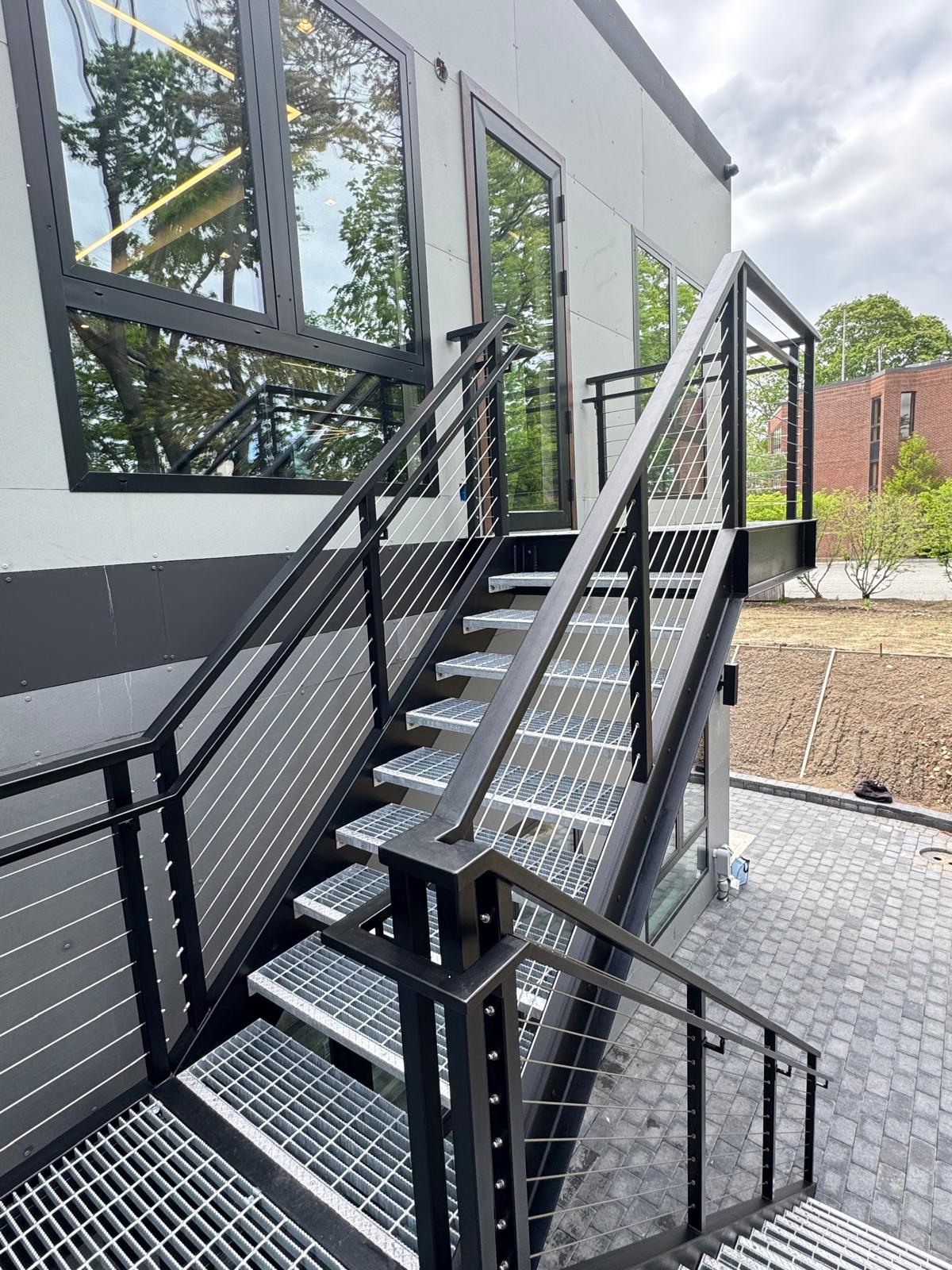 Black steel exterior stair with cable railing and grating treads